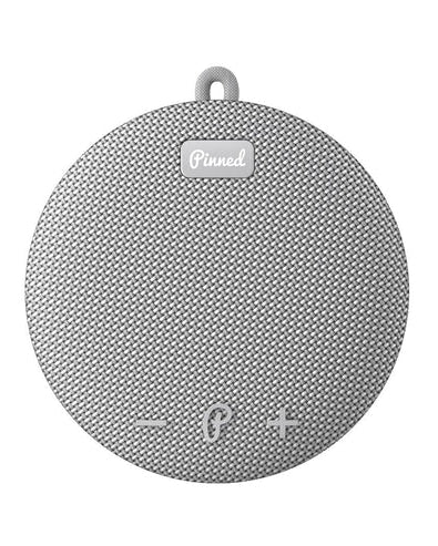 Round gray textured Bluetooth speaker with 'Pinned' logo on a white background